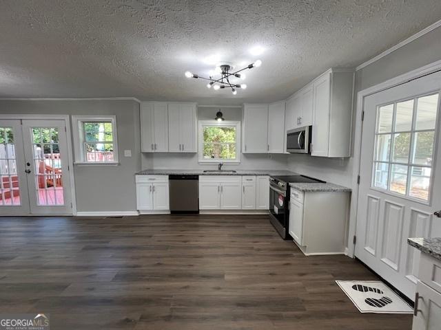 kitchen with dark wood-type flooring, appliances with stainless steel finishes, and white cabinetry