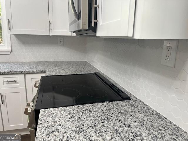 kitchen featuring white cabinetry, light stone countertops, appliances with stainless steel finishes, and dark hardwood / wood-style floors