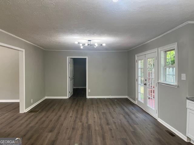 empty room featuring dark wood-type flooring, baseboards, visible vents, and ornamental molding