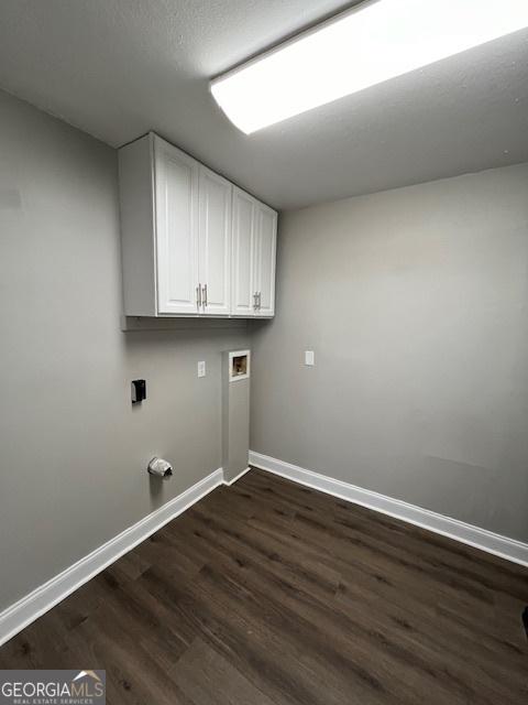 laundry area featuring cabinet space, baseboards, hookup for a washing machine, and dark wood finished floors