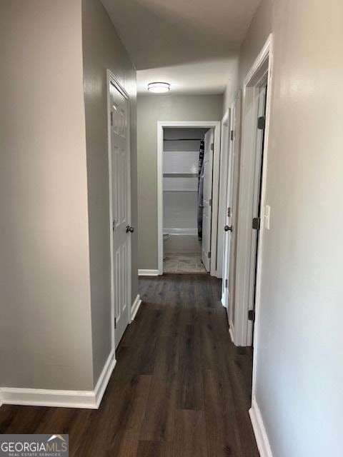 corridor with baseboards and wood finished floors