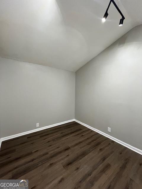 additional living space with dark wood-type flooring, baseboards, and lofted ceiling