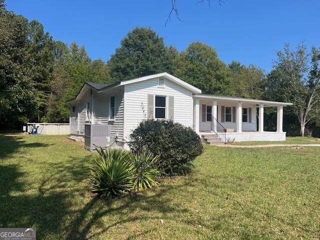 view of front facade featuring covered porch, central AC unit, and a front yard