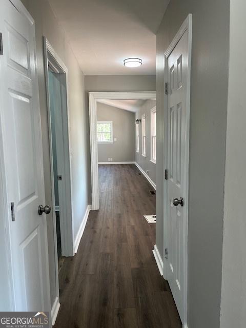 corridor with dark wood-type flooring and baseboards