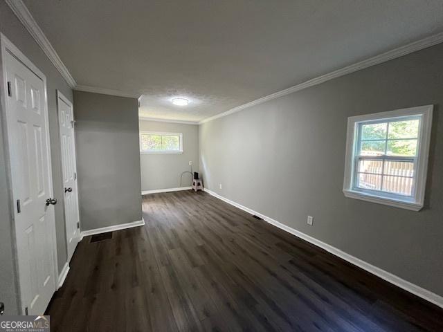 interior space featuring baseboards, dark wood-style flooring, and ornamental molding