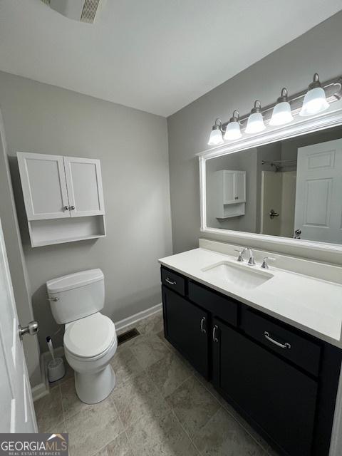 full bath featuring vanity, baseboards, visible vents, walk in shower, and toilet