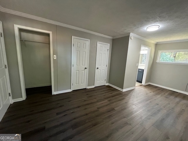 unfurnished bedroom featuring crown molding, two closets, dark hardwood / wood-style floors, and a textured ceiling