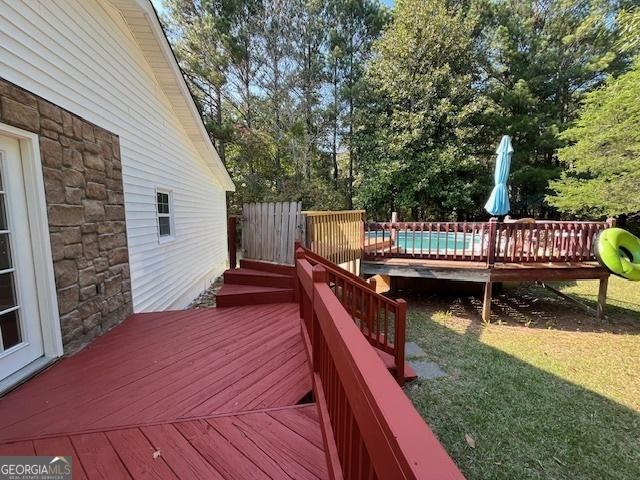 wooden deck featuring a fenced in pool and a lawn