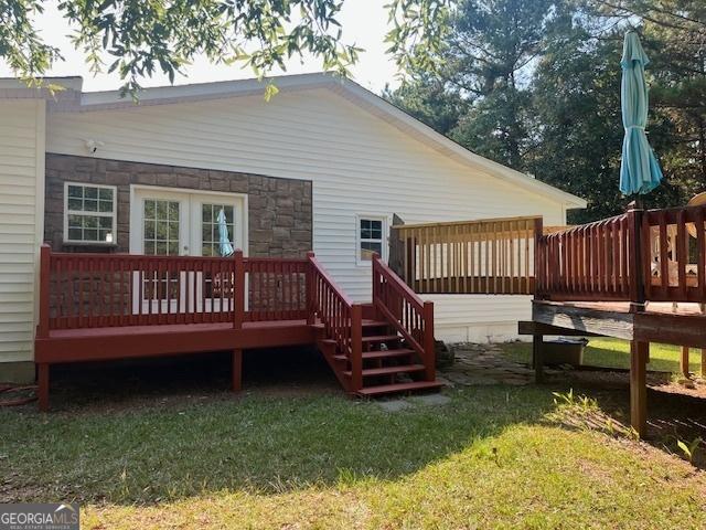 back of house featuring a deck, a yard, and stone siding