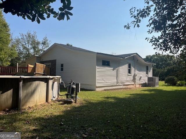 view of home's exterior featuring a pool, central air condition unit, and a lawn