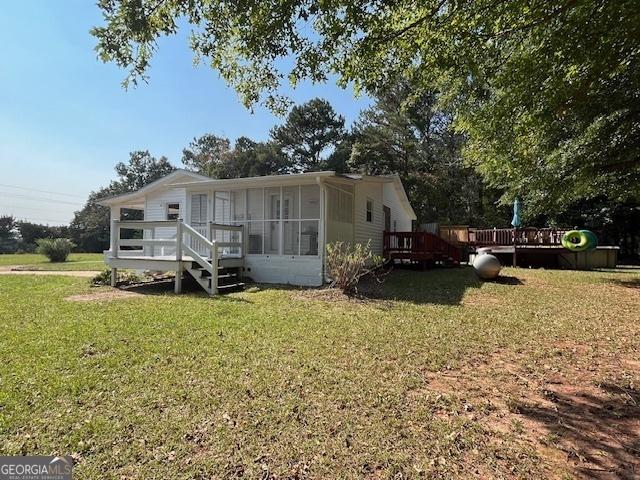 view of front of property with a front lawn, a deck, and a sunroom