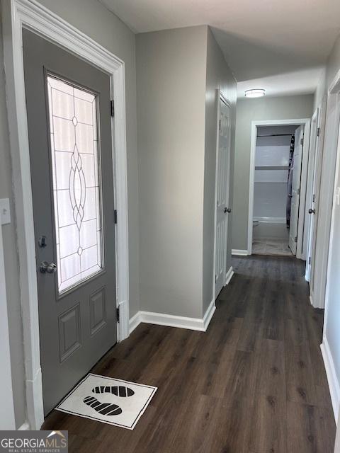 foyer featuring dark wood-type flooring and baseboards