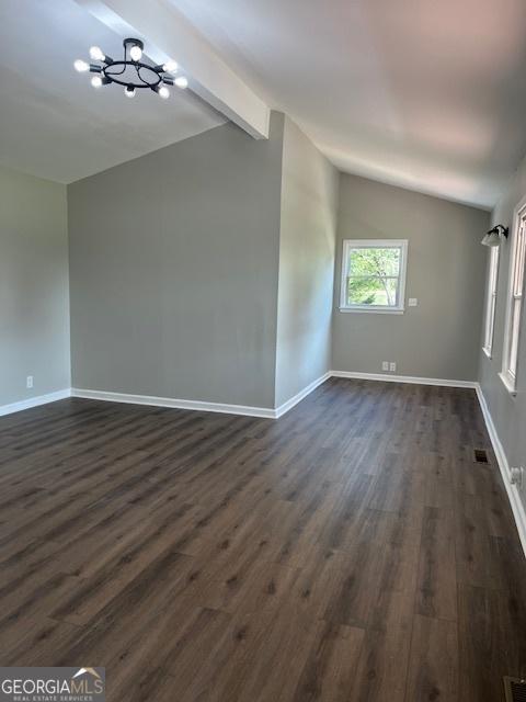 spare room featuring lofted ceiling with beams, dark wood-style floors, baseboards, and visible vents