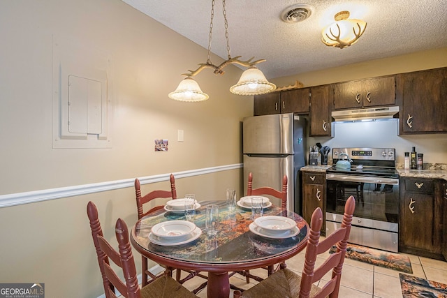 kitchen with hanging light fixtures, light tile patterned floors, appliances with stainless steel finishes, a textured ceiling, and dark brown cabinetry