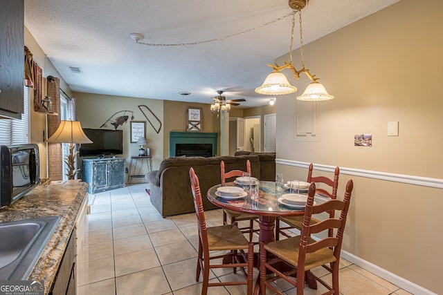 dining room featuring sink, light tile patterned flooring, a textured ceiling, and ceiling fan