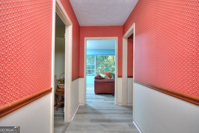 hall with light hardwood / wood-style flooring and a textured ceiling