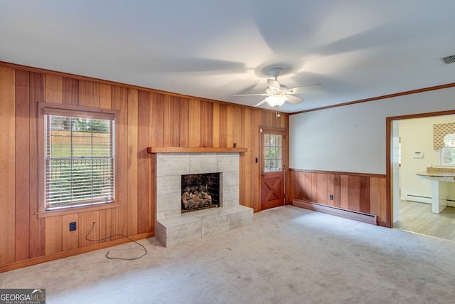 unfurnished living room featuring a fireplace, a healthy amount of sunlight, a baseboard heating unit, and ornamental molding