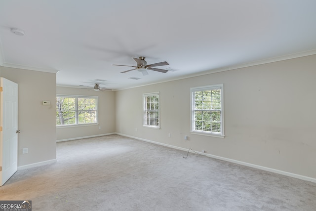 spare room with light colored carpet, ceiling fan, plenty of natural light, and ornamental molding