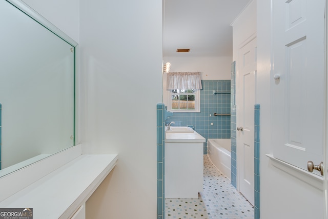 bathroom featuring a bath, vanity, and tile walls