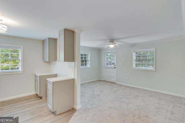 kitchen with a wealth of natural light, light carpet, ceiling fan, and crown molding