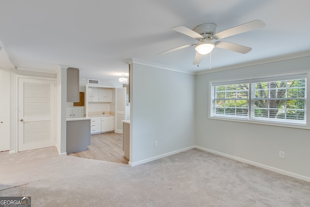 carpeted spare room featuring sink, ceiling fan, and crown molding