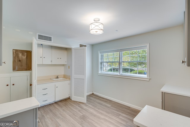 interior space featuring white cabinetry, light wood-type flooring, and sink