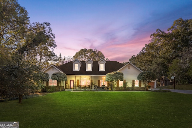 new england style home with covered porch and a lawn