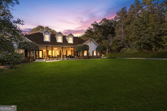 cape cod house featuring a lawn