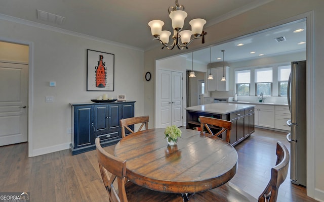 dining space featuring dark wood-type flooring, a notable chandelier, and crown molding