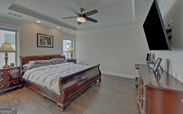 bedroom with ceiling fan, dark wood-type flooring, and a raised ceiling