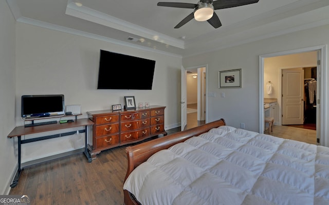 bedroom with ensuite bathroom, a tray ceiling, wood-type flooring, and ceiling fan