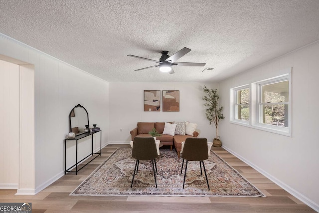 living room with a textured ceiling, light hardwood / wood-style flooring, and ceiling fan