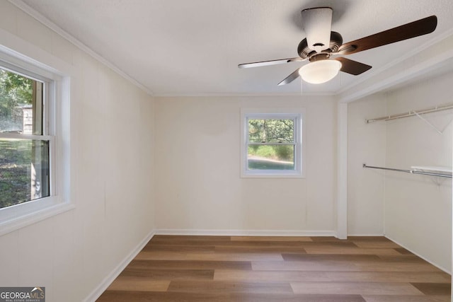 unfurnished room featuring plenty of natural light, wood-type flooring, and crown molding