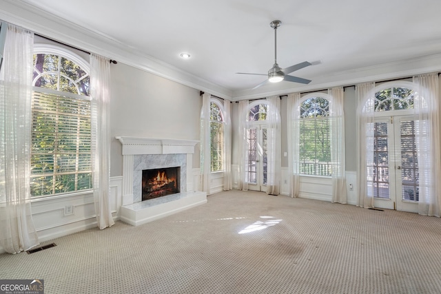 unfurnished living room featuring crown molding, a fireplace, light colored carpet, and ceiling fan