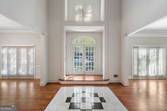 foyer entrance featuring french doors, dark wood-type flooring, a high ceiling, and crown molding