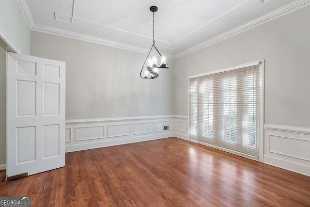 empty room featuring an inviting chandelier, ornamental molding, and hardwood / wood-style flooring