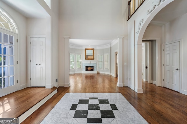 foyer entrance with ornate columns, ornamental molding, a high ceiling, and dark hardwood / wood-style flooring