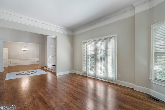 interior space featuring dark wood-type flooring, ornamental molding, and a chandelier