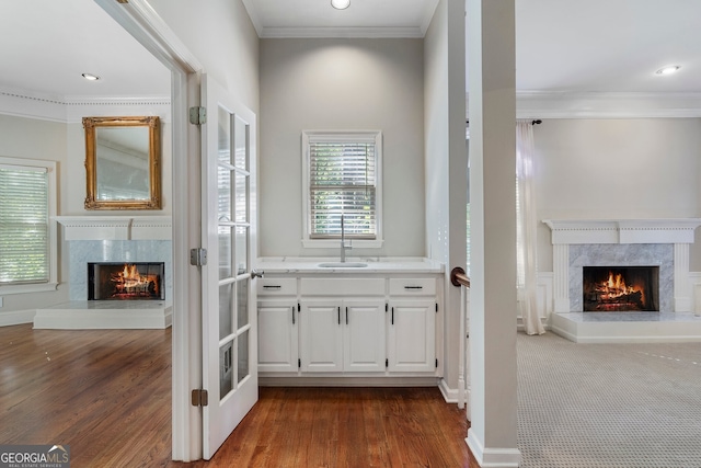 bar featuring sink, a high end fireplace, white cabinetry, ornamental molding, and dark hardwood / wood-style floors