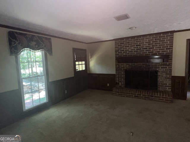 unfurnished living room featuring wooden walls, crown molding, carpet, a brick fireplace, and a textured ceiling