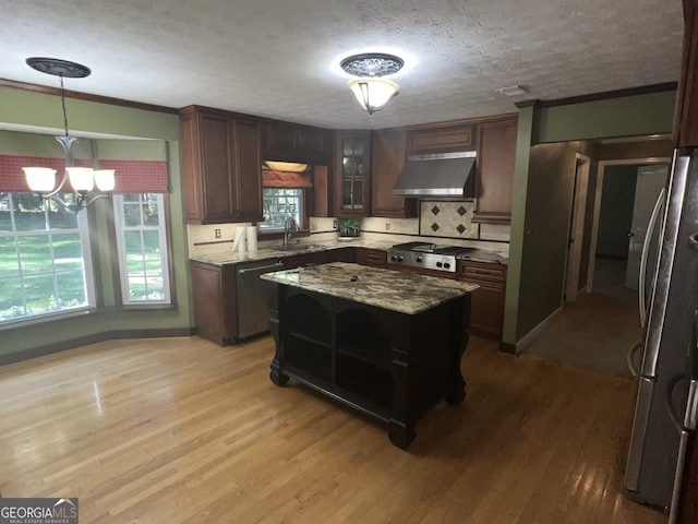 kitchen with appliances with stainless steel finishes, decorative light fixtures, a notable chandelier, light hardwood / wood-style flooring, and ventilation hood