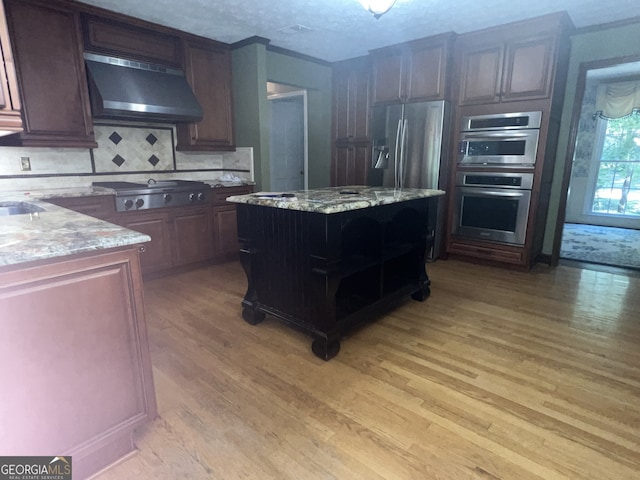 kitchen with light hardwood / wood-style flooring, range hood, a center island, appliances with stainless steel finishes, and light stone counters