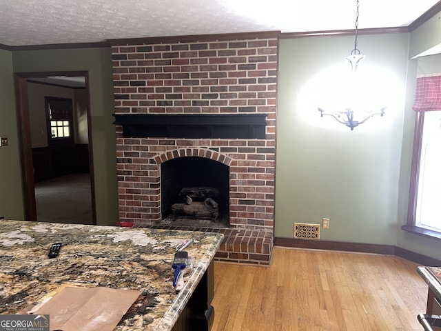 living room with light hardwood / wood-style flooring, a textured ceiling, crown molding, and a brick fireplace