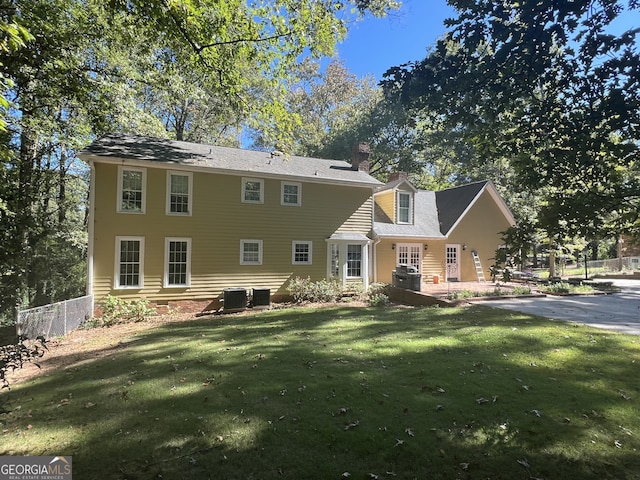 back of property with a yard and central air condition unit