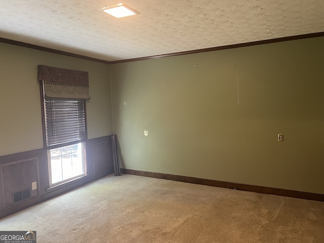 carpeted empty room with crown molding and a textured ceiling