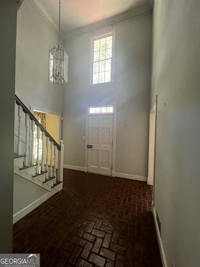 foyer featuring a towering ceiling, crown molding, and a notable chandelier