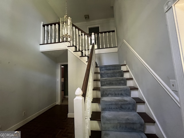 stairs with a notable chandelier, ornamental molding, and a high ceiling