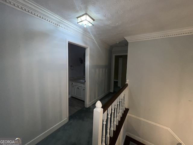 hall featuring ornamental molding, dark colored carpet, and a textured ceiling