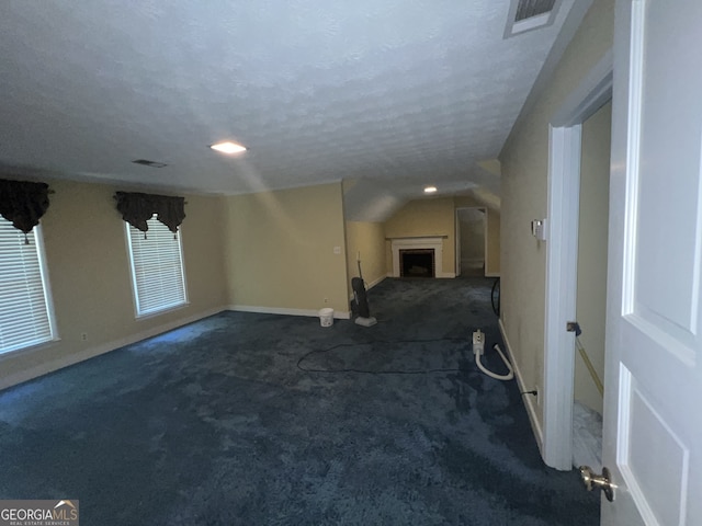 carpeted empty room with a textured ceiling and lofted ceiling