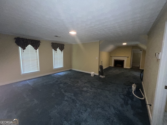 unfurnished living room featuring carpet floors, a textured ceiling, and vaulted ceiling